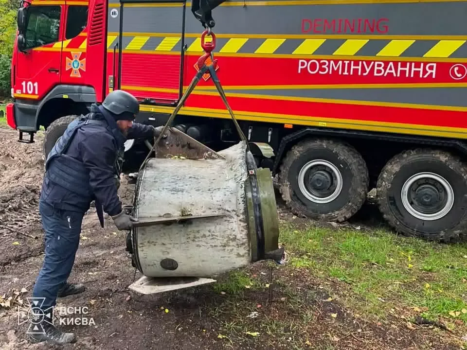 Рятувальник ДСНС направляє уламок ракети, який кран піднімає біля машини розмінування