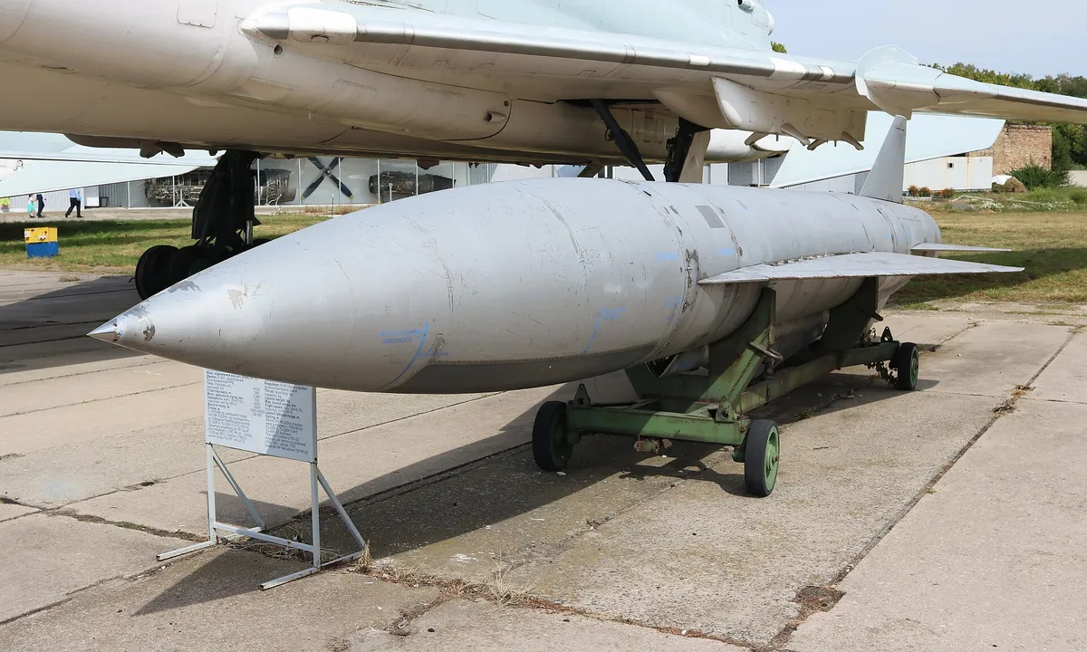 Сіра ракета Х-22 з гострим носом на візку під крилом бомбардувальника в музеї